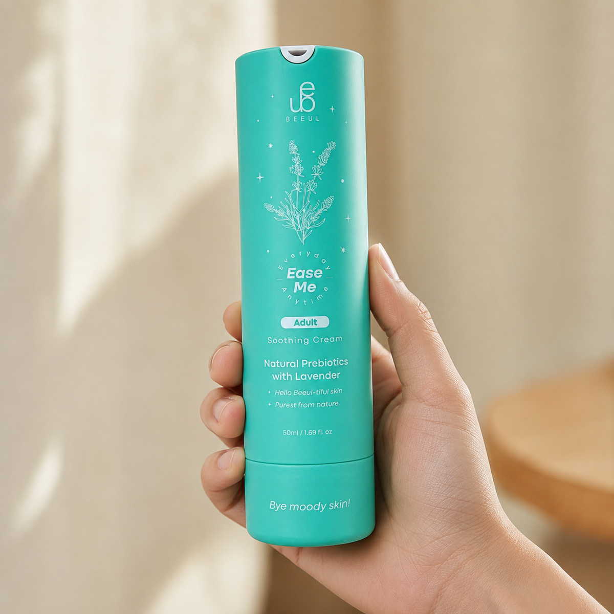 A hand holding the turquoise BEEUL Ease Me Adult 50g tube against a sunlit wall