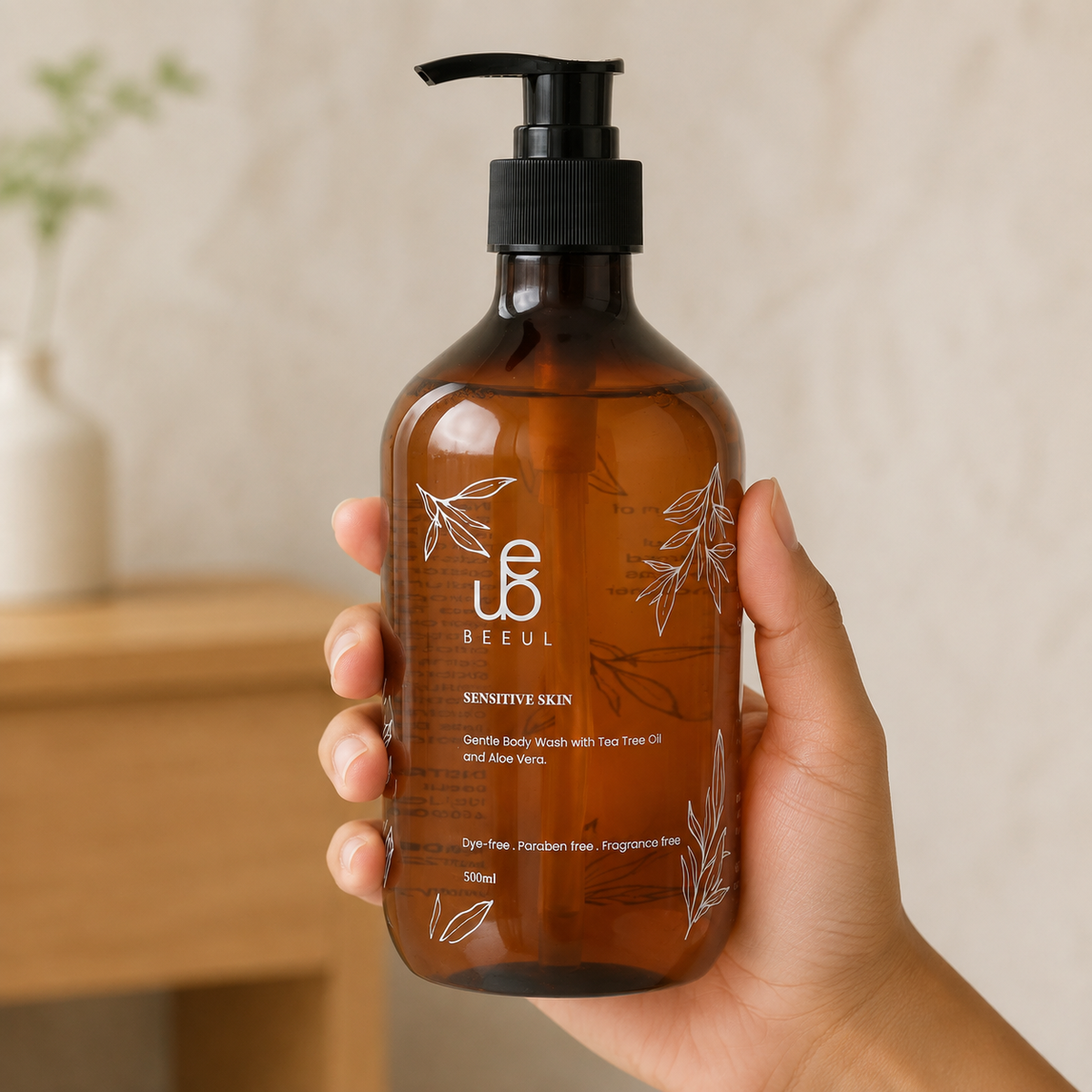 A hand holding the amber 500ml BEEUL Gentle Body Wash pump bottle in a bright room